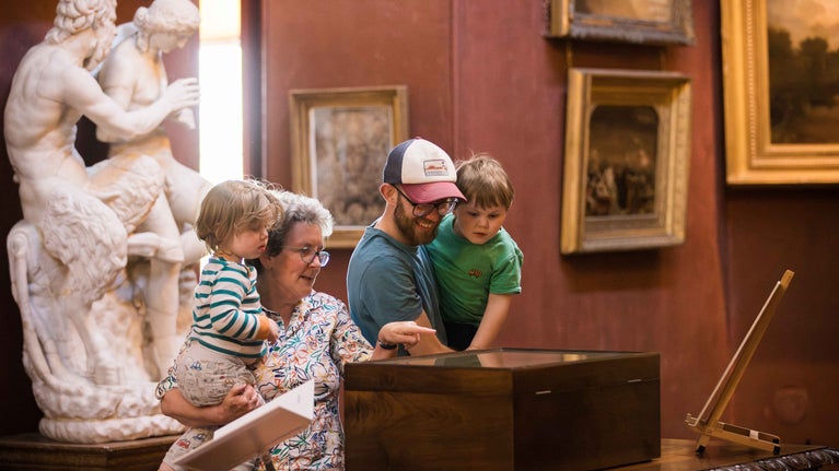 A family exploring the collection in the North Gallery at Petworth House, West Sussex